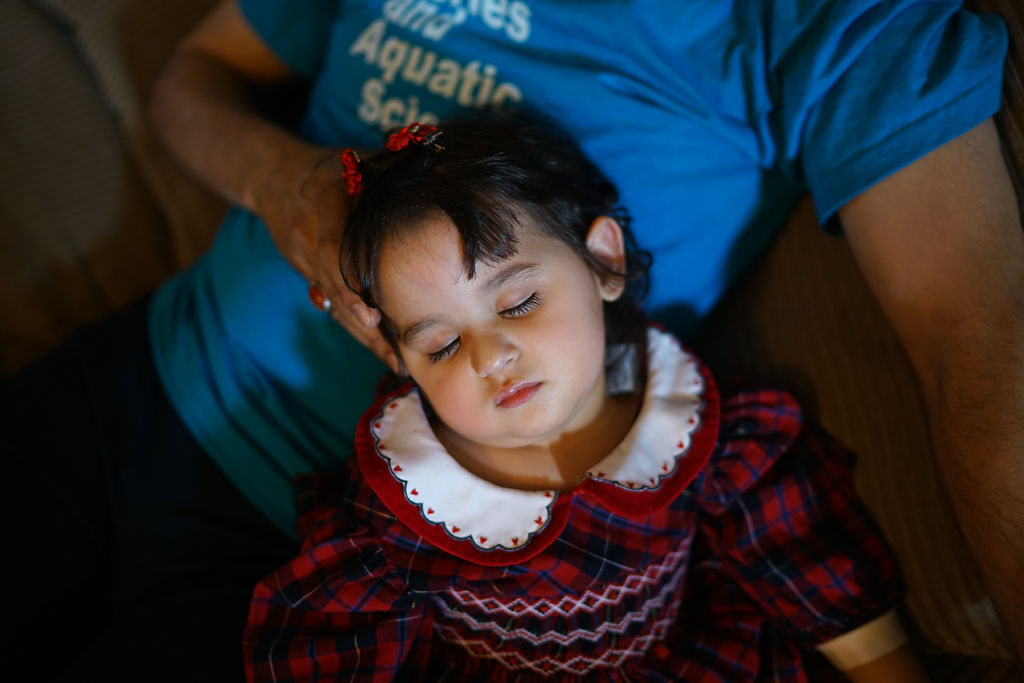 Zahra Al Hraishawi, 1, sleeps on her father Mohammed Al Hraishawi's lap